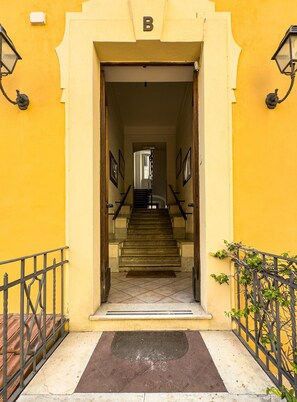 A building entrance with a staircase leading to a landing, a doormat, and a letter 'B' above the entrance. - VATICAN ROOMS DORIA  (Rome)