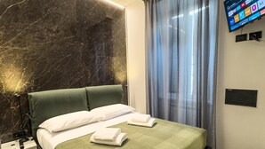 A modern hotel room with a large bed, a flat-screen TV mounted on the wall, and a marble accent wall. - VATICAN ROOMS DORIA  (Rome)