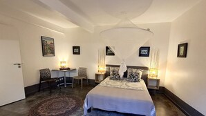 Un dormitorio con cama, lámparas de noche, una silla y una alfombra.