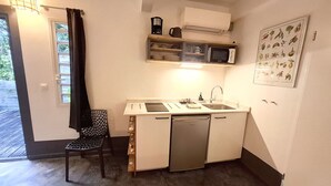 Una cocina compacta con lavavajillas, microondas y un estante pequeño con utensilios de cocina.