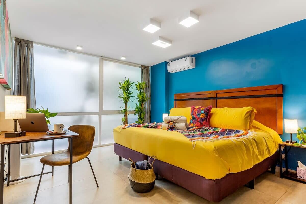 Camera d'albergo con un letto, una scrivania, una sedia e un'ampia finestra.