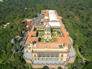 A large, historic building with multiple towers and a central courtyard, surrounded by dense forest. - Colorful Condesa 4BR with garden balcony, AC (Mexico City)