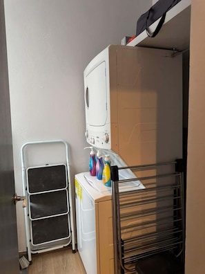 A laundry area with a washing machine, a drying rack, and detergent bottles. - Colorful Roma Norte 3BR/3BA, 2 patios, AC (Mexico City)