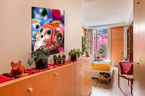 A modern bedroom with a bed, bedside table, and a large painting. - Colorful Roma Norte 3BR/3BA, 2 patios, AC (Mexico City)