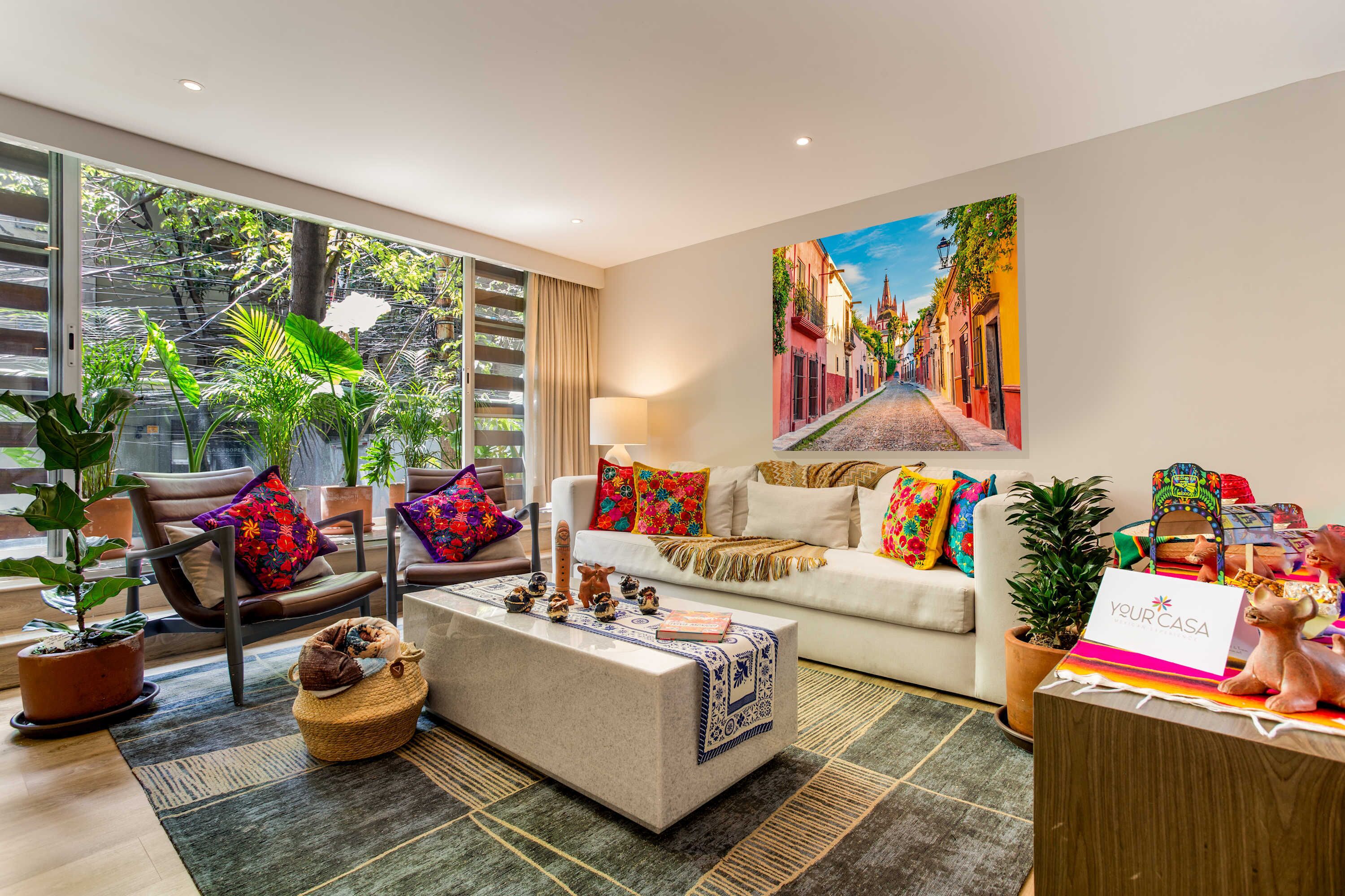A modern living room with a sofa, chairs, a coffee table, and a painting of a street scene.