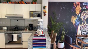 Et moderne køkken med en central ø, mikroovn, komfur og kaffemaskine.