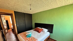 Ein Hotelzimmer mit einem Bett, einem Kopfteil, einer grünen Wand, einem Holzboden und einer Decke mit einem strukturierten Muster.