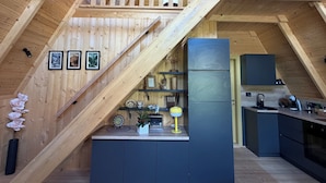 Un intérieur de style industriel, avec des éléments en bois, comprenant un espace cuisine, un escalier et un petit balcon.