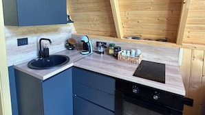 Une cuisine de taille réduite équipée d’un évier, d’une machine à café et d’une cuisinière.