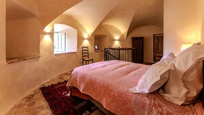 A bedroom with a bed, a red rug, a wooden chair, and a window. - Tour Ouest Vacation Rental - Château de Vachères (Montclar-sur-Gervanne)