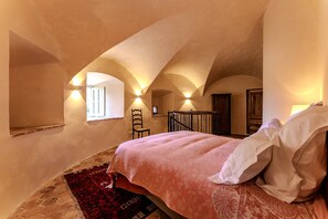 Ein Schlafzimmer mit einem Bett, einem roten Teppich, einem Holzsessel und einem Fenster.