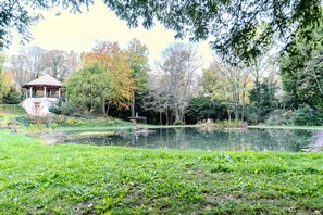 Ein Pavillon, ein Teich und umgebende Bäume.