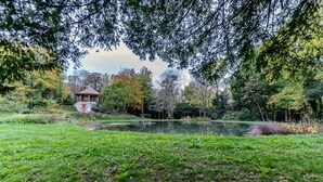 A gazebo in a park with a pond and trees. - Tour Est Vacation Rental at Château de Vachères. (Montclar-sur-Gervanne)