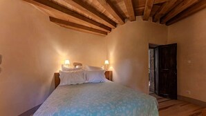 A bedroom with a bed, two bedside lamps, and a wooden ceiling. - Tour Est Vacation Rental at Château de Vachères. (Montclar-sur-Gervanne)