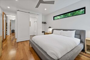 A modern bedroom with a large bed, a walk-in closet, and a window with a view of greenery. - Rooftop Oasis in Historic St. Augustine Panoramic Intracoastal Waterway Views (St. Augustine)