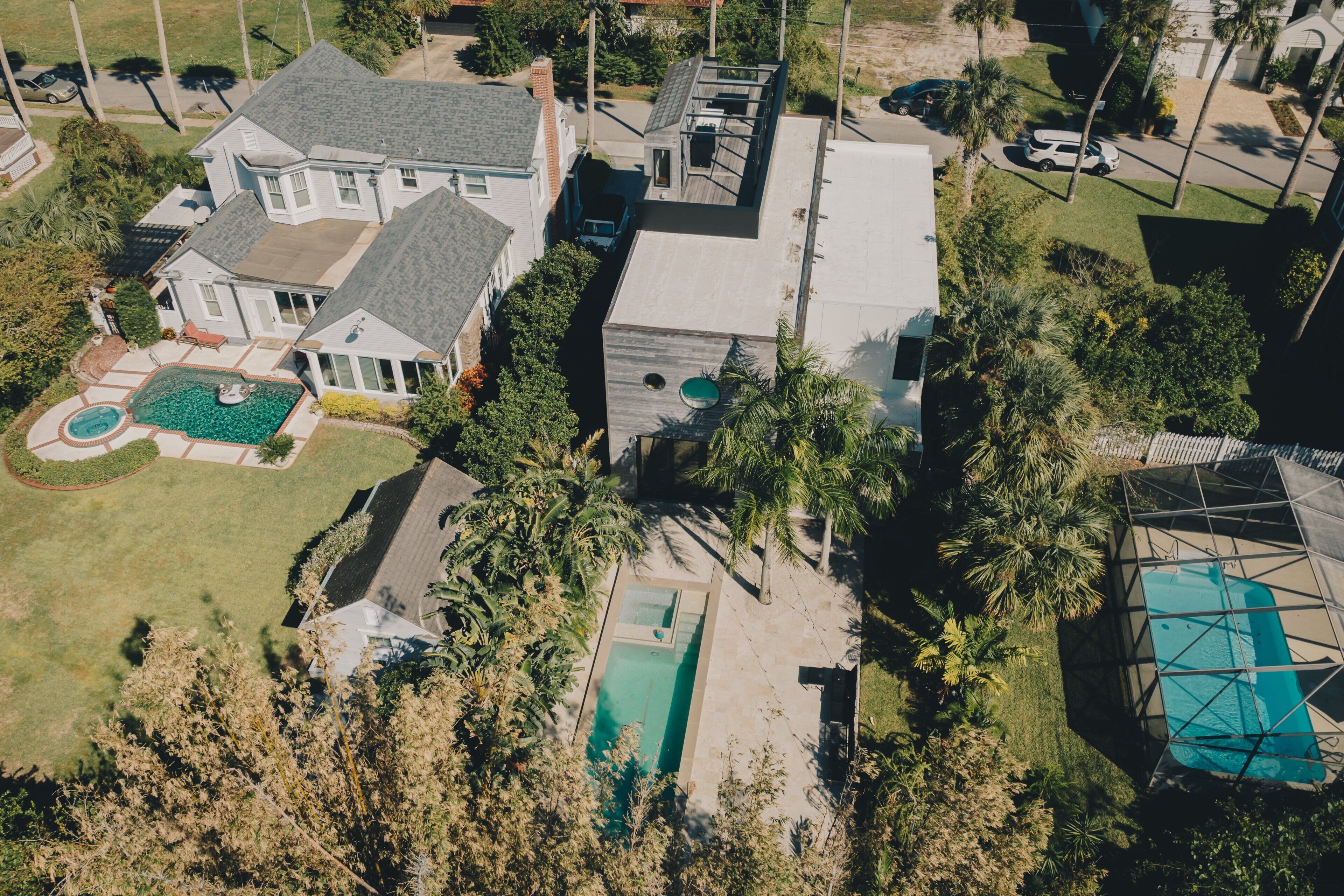 A large house with a swimming pool, a tennis court, and a fenced yard.