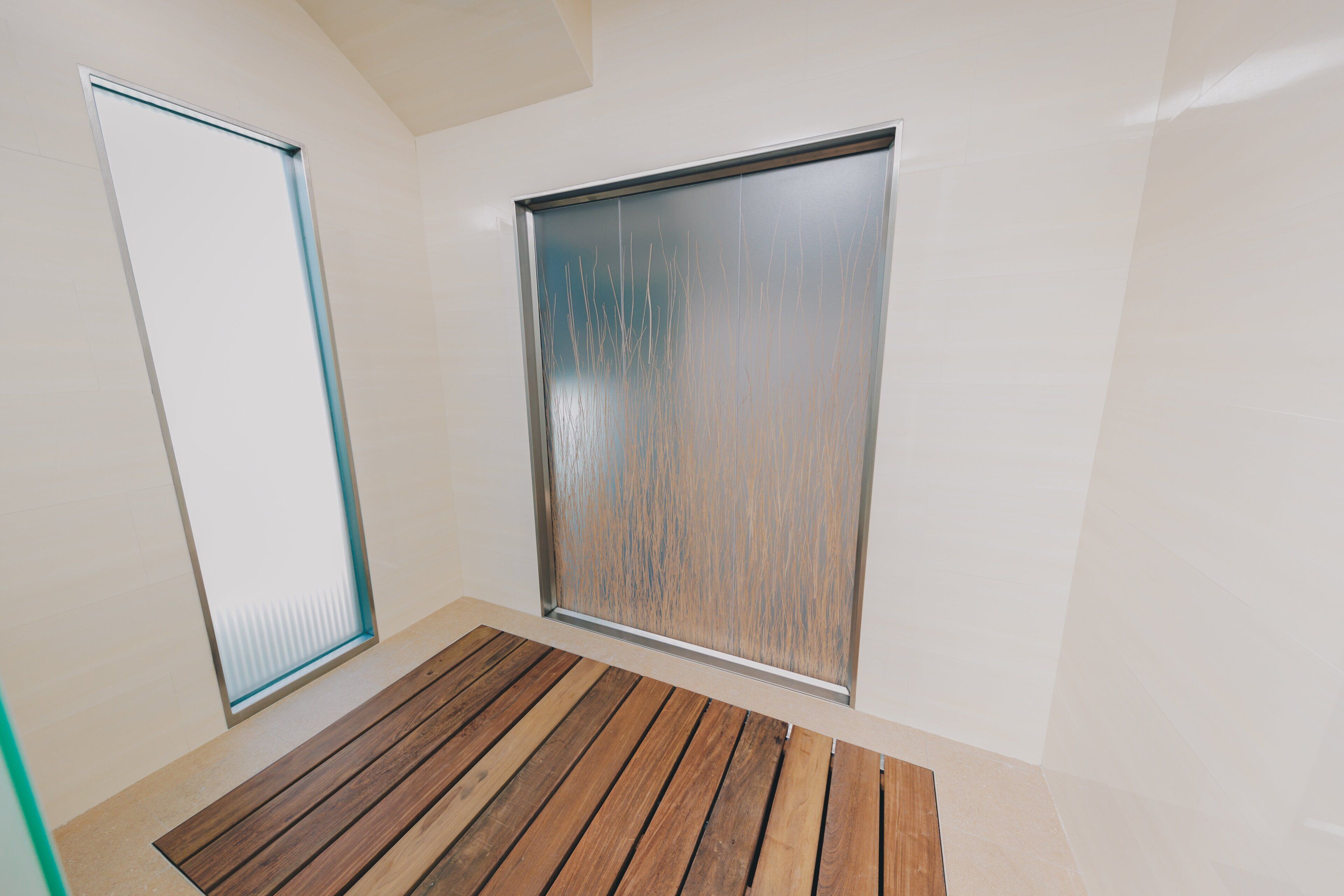 A room with a wooden floor, a large frosted glass window, and a door.