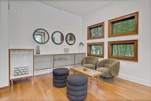Ein modernes Wohnzimmer mit einer Couch, Poufs, einem Couchtisch und einem Glaskabinett mit Weingläsern.
