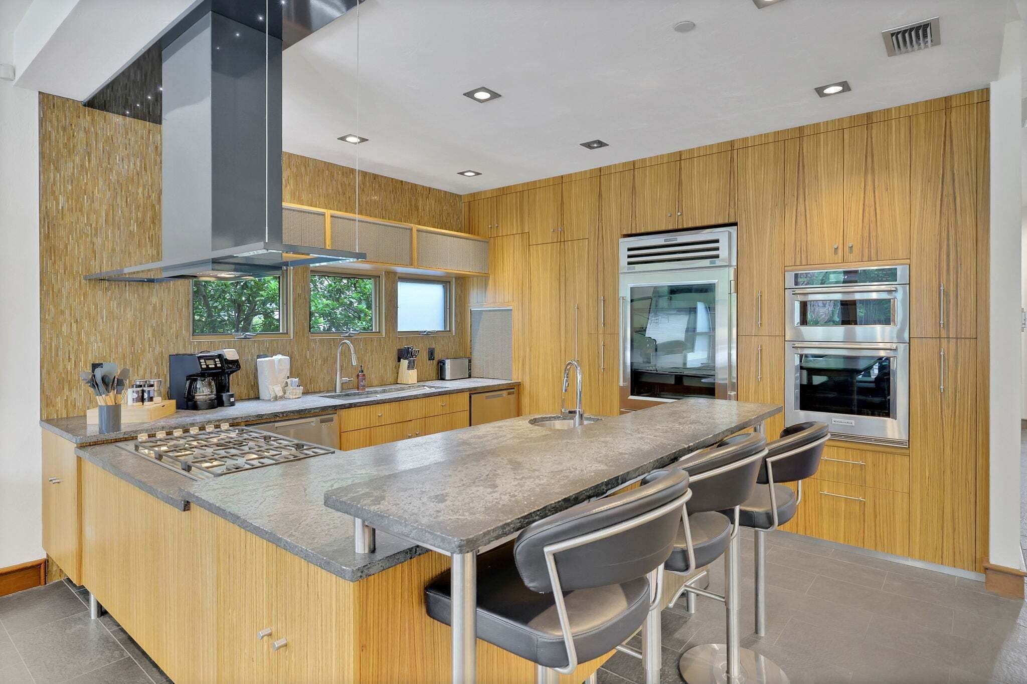 A modern kitchen with wooden paneling, stainless steel appliances, and a central island with bar stools.