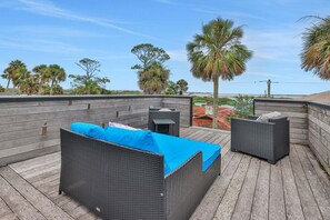 An outdoor seating area with wicker furniture and a blue cushion, overlooking a coastal landscape. - Rooftop Oasis in Historic St. Augustine Panoramic Intracoastal Waterway Views (St. Augustine)