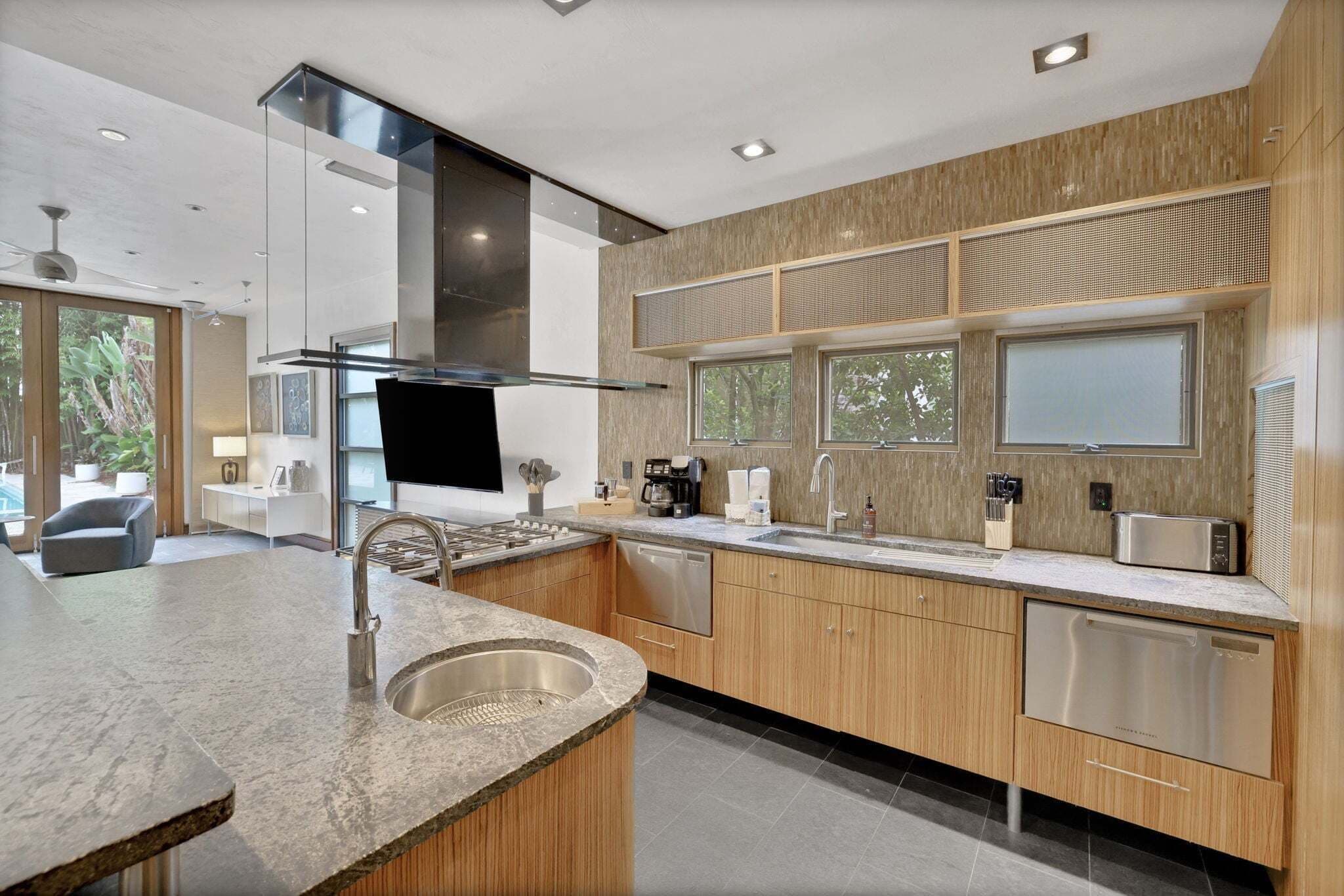 A modern kitchen with a central island, stainless steel appliances, and wooden cabinetry.