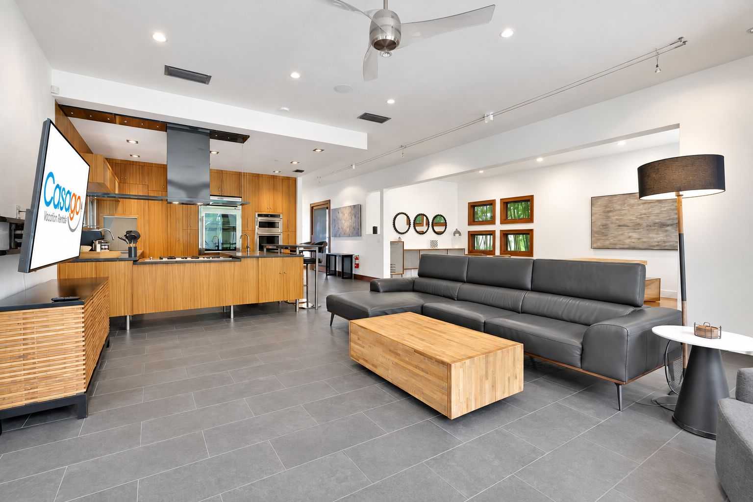 A modern hotel lobby with a kitchen area, a seating area with a sofa and coffee table, and a reception desk.