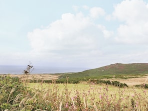 Paisaje costero con colinas ondulantes, campos y cielo despejado.