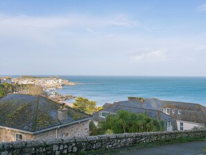 A coastal town with stone buildings, a stone wall, and a view of the sea. - Ninevah (St Ives)