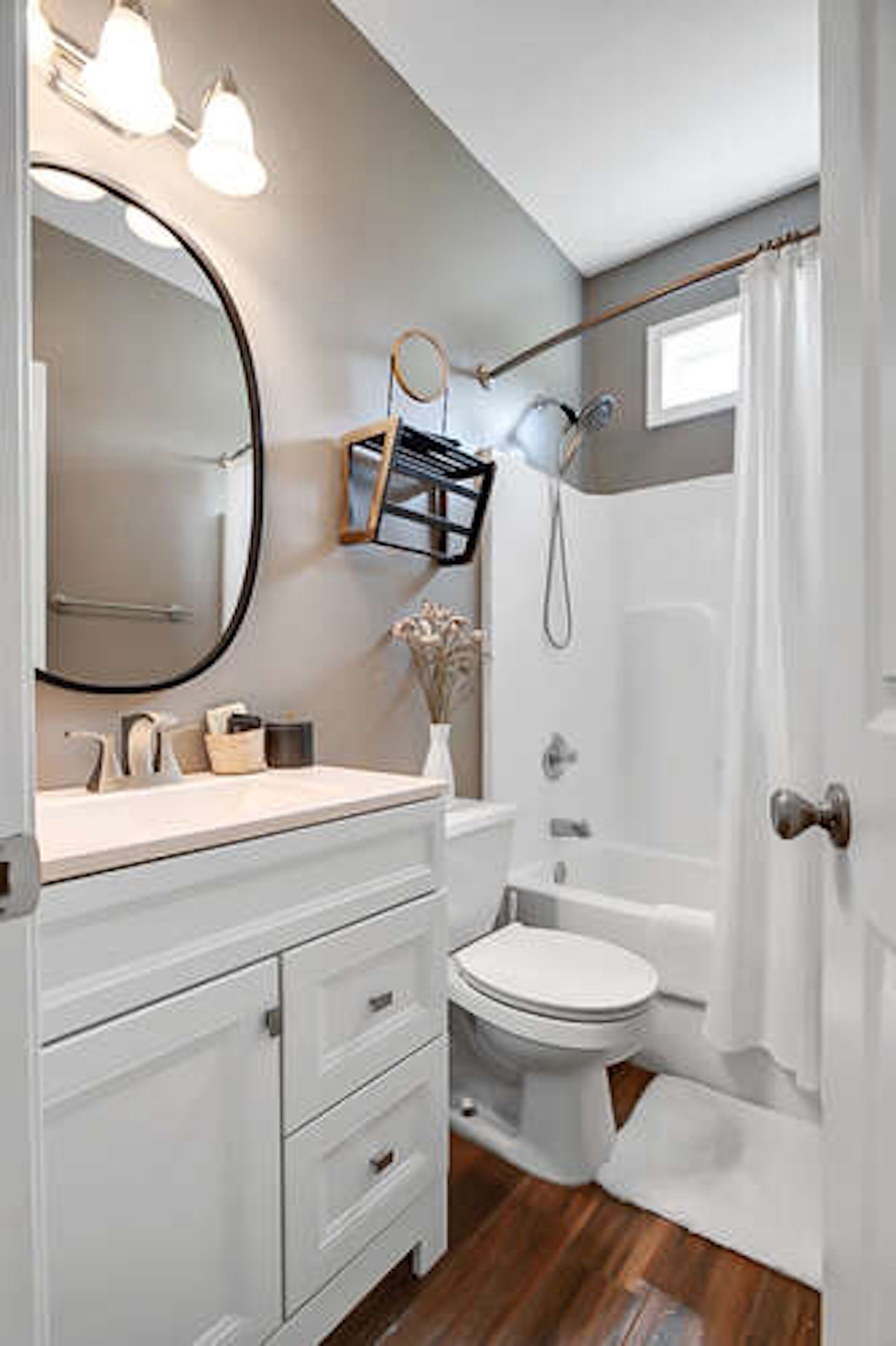 A bathroom with a white vanity, a large mirror, a toilet, a bathtub, and a shower.