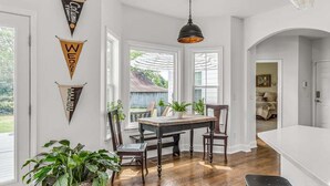 Un comedor con mesa y sillas, una lámpara colgante y vistas al exterior.