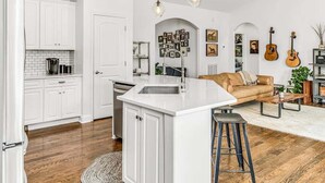 Una cocina moderna con armarios blancos, una isla central y un taburete de bar.