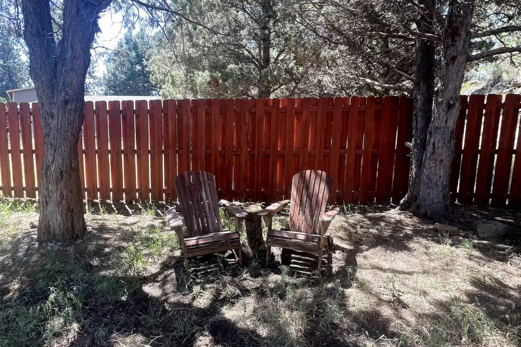 A fenced backyard with two wooden chairs and a small table.