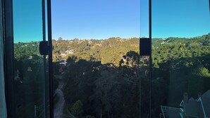 A large window with a clear view of a hilly landscape and a road below. - Le Bonne Ville Hotel (Campos do Jordão)