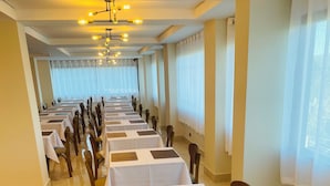 A hotel conference room with rows of tables, chairs, and a chandelier. - Le Bonne Ville Hotel (Campos do Jordão)