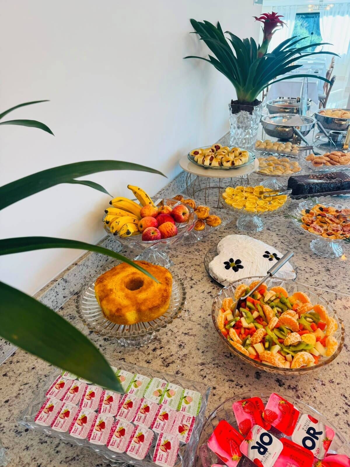 Uma mesa de buffet com diversos alimentos, incluindo frutas, doces e produtos embalados.