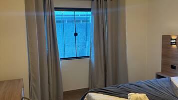 Ein Hotelzimmer mit einem Bett, einem Schreibtisch, einem Stuhl und einem fensterbepflanzten Fenster.