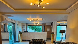 A modern hotel lobby with a leather sofa, a round coffee table, and a chandelier. - Le Bonne Ville Hotel (Campos do Jordão)