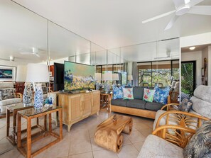 A modern living room with a large flat-screen TV, a sofa, wicker chairs, and a wooden coffee table. - Wailea Ekahi Village 20D (Wailea)