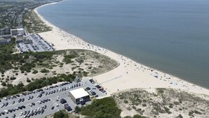 An aerial view of a beach with a parking lot and buildings.