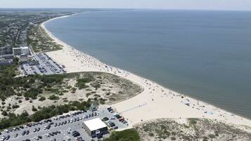 Luchtbeeld van een strand met een parkeerplaats en gebouwen.