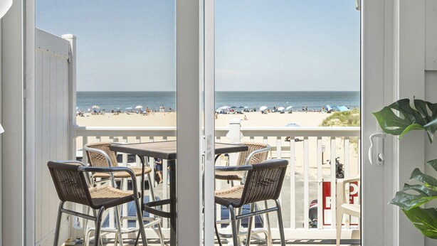 A balcony with wicker chairs and a view of the beach.