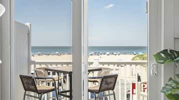 Een balkon met rieten stoelen en uitzicht op het strand.