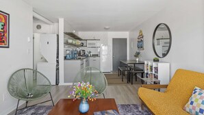 A modern living room with a sofa, chairs, a coffee table, and a dining area with a table and chairs.