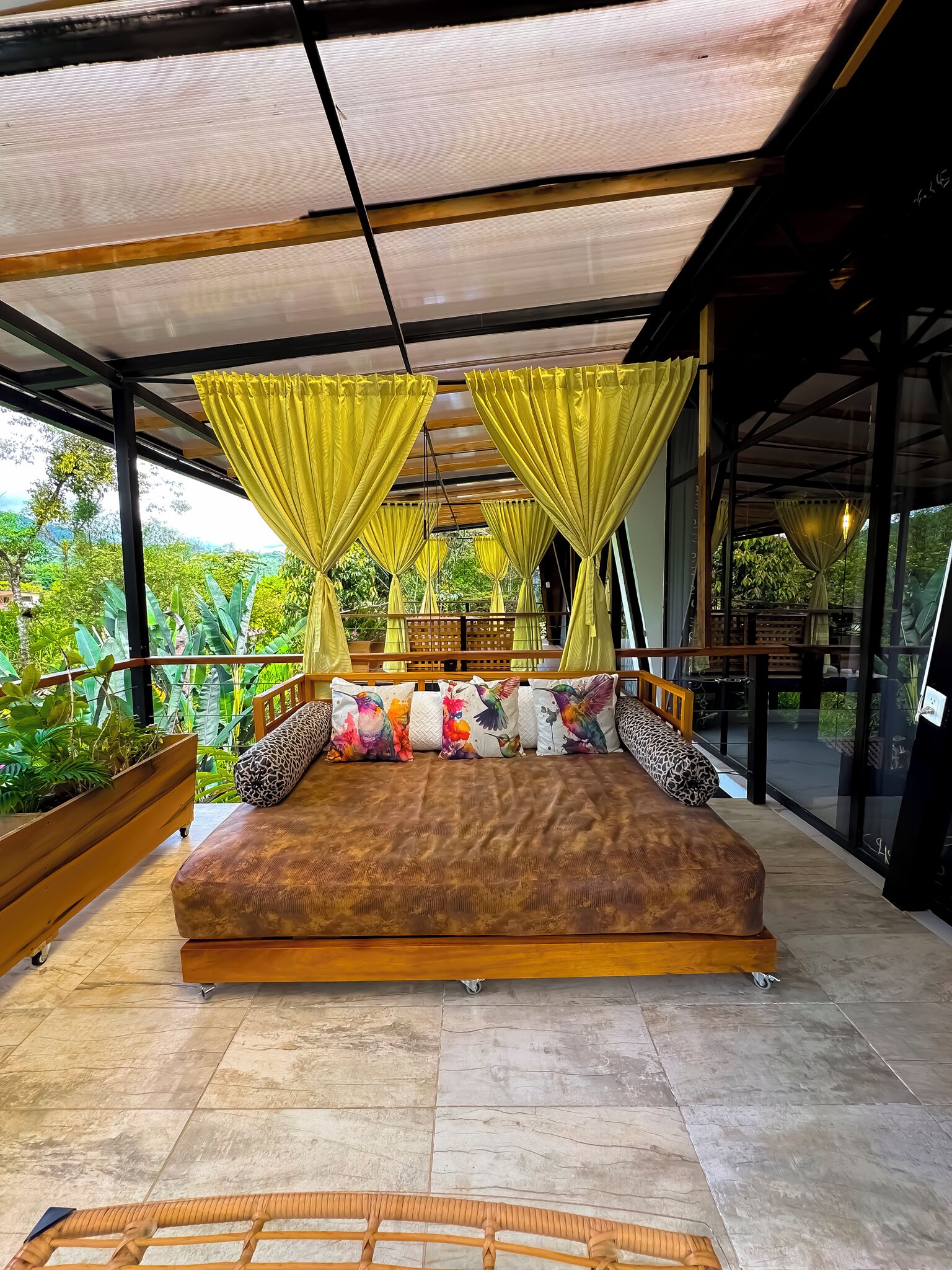 Una habitación amplia con una cama grande, cortinas amarillas y vistas al paisaje exterior.