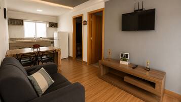 Una sala de estar moderna con un sofá, una mesa de centro y un televisor montado en la pared.