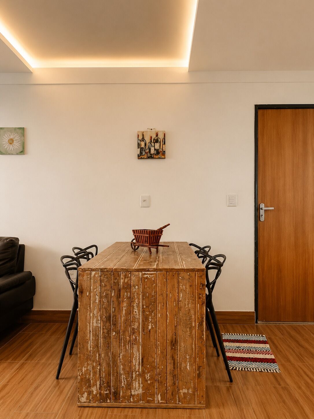 A dining area with a wooden table, metal chairs, a small wooden cart, and a door.
