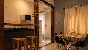 Una cocina compacta con microondas, refrigerador y taburetes de madera.