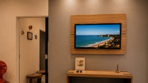 Una sala de estar moderna con un televisor montado, una mesa consola de madera y una puerta que da a otra habitación.
