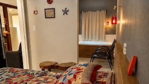 Un dormitorio con una cama, una silla, una mesita y una ventana con cortinas.