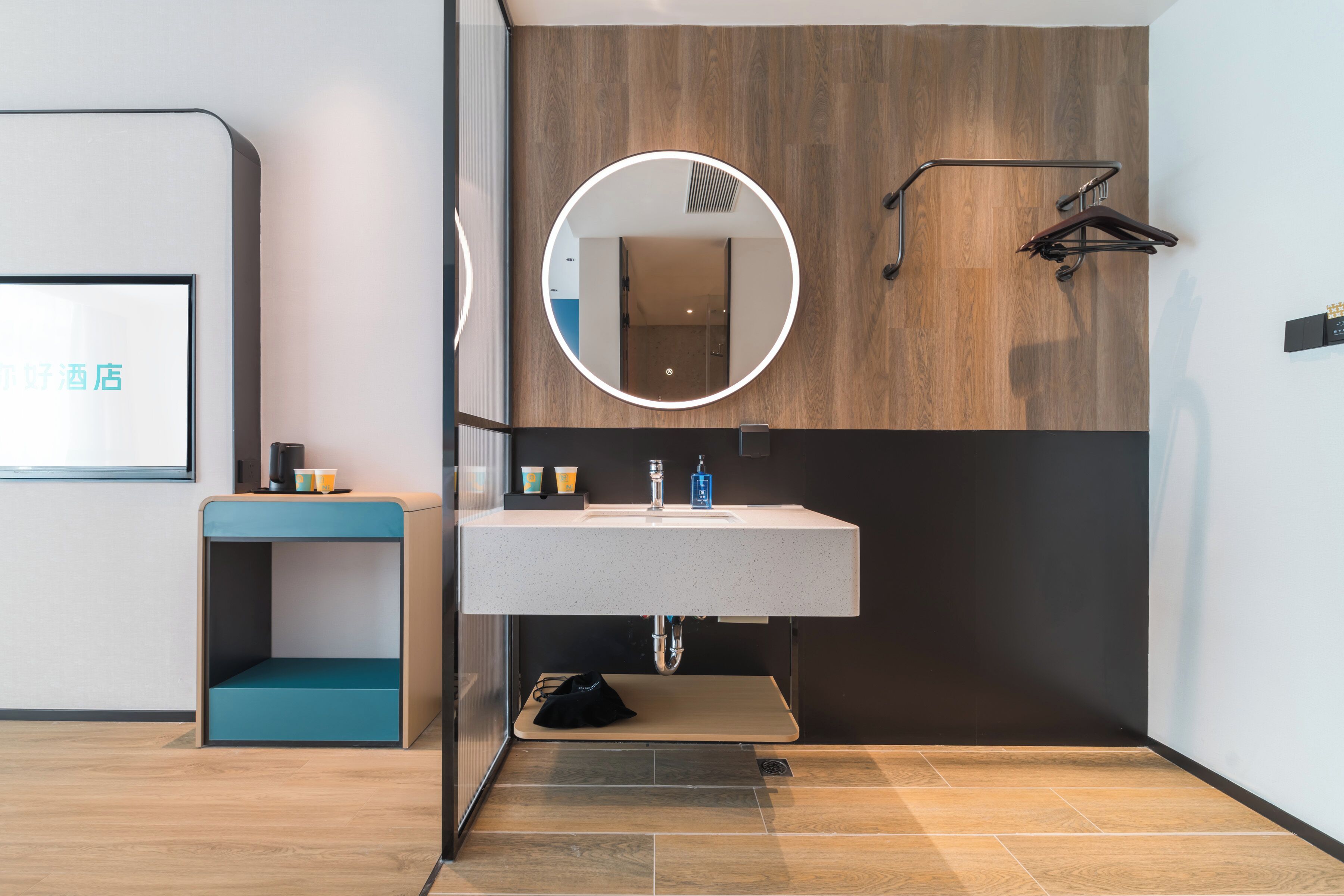 Un baño moderno con un espejo redondo, un lavamanos y un revestimiento de pared de madera.
